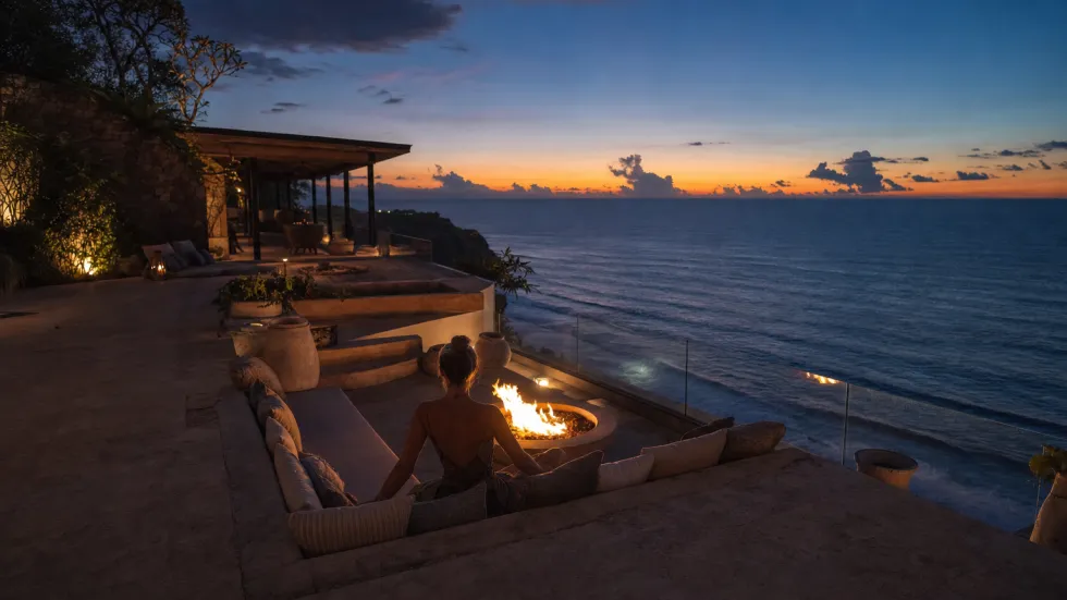 Lounge perapian di tebing saat senja di atas samudra lepas